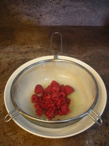 Squeeze raspberries over strainer to extract juice
